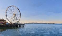 a ferris wheel sitting on top of a pier next to the ocean