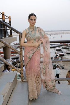 a woman in a pink sari standing on some steps