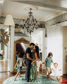 a man and woman are kissing in front of children on the floor with chandelier