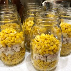 several glass jars filled with corn on top of a table