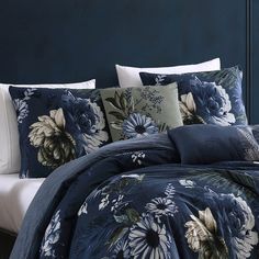 a bed with blue and white flowers on the comforter, pillows and pillow cases