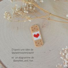 a cross stitch bookmark sitting on top of a tree stump next to some flowers