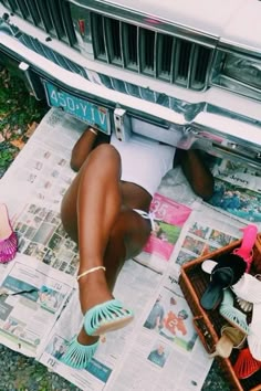 a woman laying on top of a newspaper next to a car