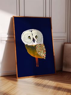 an owl is sitting on the floor in front of a blue background and wooden frame