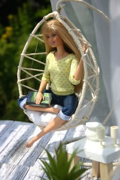 a doll is sitting in a hammock with a laptop