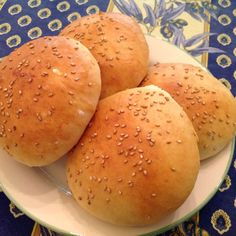 three buns sitting on top of a white plate with sesame seed sprinkles