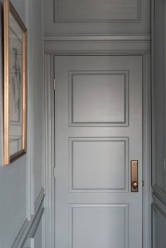 an empty hallway with a white door and mirror on the wall, in front of it