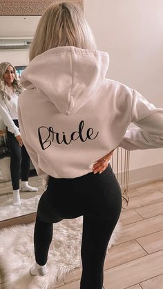 a woman in black leggings and a white hoodie with the word bride printed on it