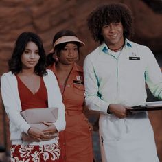 three people standing next to each other in front of a rock wall and holding a clipboard