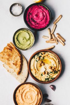 hummus, pita bread and dips on a white surface