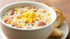 a bowl of soup with ham and cheese in it next to some crackers on the side