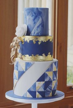 a three tiered cake with blue and gold decorations