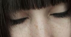 a close up of a woman's face with freckles on her eyes