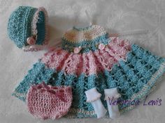 a crocheted dress, hat and booties are laying on a white surface