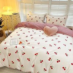 a bed with cherries on it in a bedroom next to a lamp and window