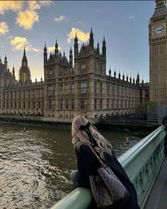 a woman standing on the side of a bridge looking at big ben