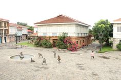 people are walking around in the courtyard of an old building with flowers growing on it