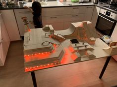 a woman is standing in the kitchen next to a table with lights on it