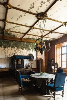 the dining room is decorated with floral wallpaper and chandelier, along with blue velvet chairs