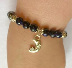 a woman's arm with a bracelet that has a gold moon and star charm on it