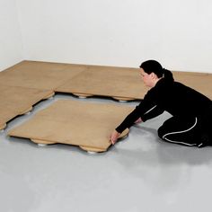 a woman kneeling on the ground with her hands in front of two pieces of cardboard