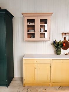 a kitchen with yellow cabinets and green cupboards next to a white counter top in front of a wooden cabinet