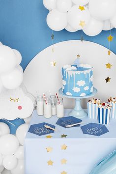 a blue and white dessert table topped with a cake next to cupcakes covered in frosting