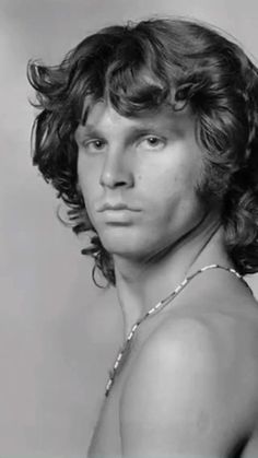 black and white photograph of a young man with curly hair wearing a tank top in front of a gray background