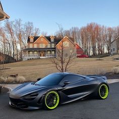 a black and yellow sports car parked in front of a large house on the street