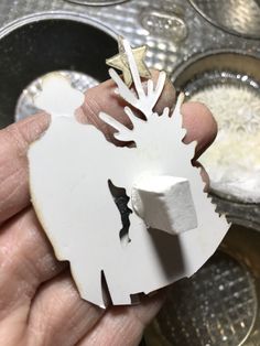 a person holding a piece of white paper in their left hand and some silver coins