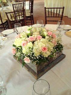 a wooden box filled with lots of white and pink flowers on top of a table