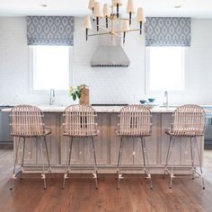 a kitchen island with four chairs and a stove in the middle, surrounded by windows