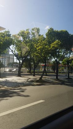 the sun is shining through some trees on the street