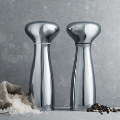 two stainless steel salt and pepper shakers on a table with spices scattered around them