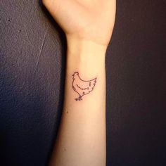 a small tattoo on the wrist of a woman's arm, depicting a chicken