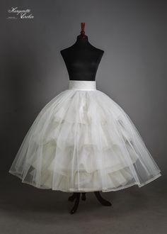 a white tulle skirt on a mannequin head stand in front of a gray background