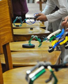 two people standing in front of wooden desks with toy glasses on top of them