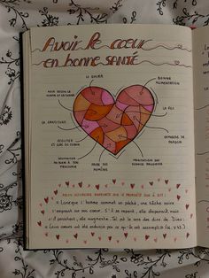 an open book with pictures of hearts and words in french on the pages, sitting on a bed