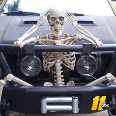 a skeleton sitting in the front of a car