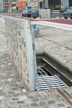 a manhole hole in the side of a road with cars parked on both sides