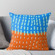 an orange and blue pillow sitting on top of a couch