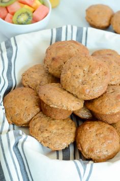 some muffins are stacked on top of each other in front of a bowl of fruit