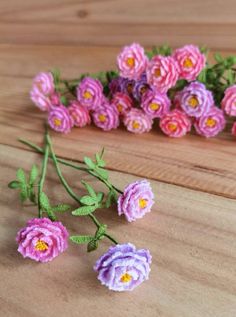 small crocheted flowers sitting on top of a wooden table