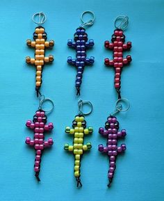 four key chains made to look like small colorful geckos on a blue background