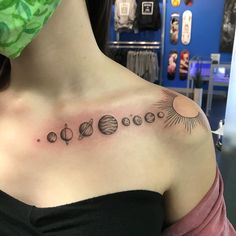 a woman with a tattoo on her shoulder that has planets and the sun in it