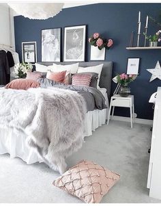 a bedroom with blue walls and white bedding is decorated in pink and grey tones