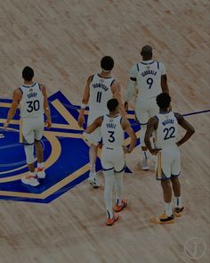 the basketball players are standing on the court talking to each other and wearing white uniforms