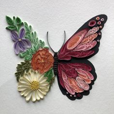 a colorful butterfly with flowers on it's wings is sitting on a white surface