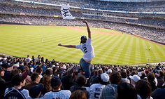 a man is jumping in the air at a baseball game while people watch from the stands