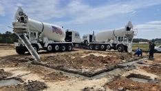 two cement trucks are parked on the ground